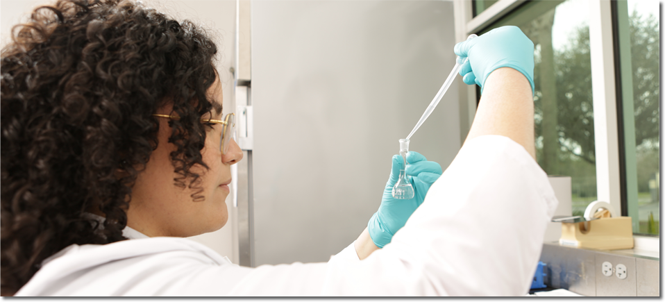 Una técnica de laboratorio agrega gotas de agua de muestra en un tubo de ensayo