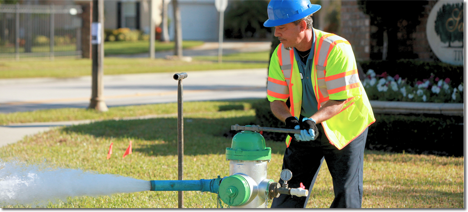 Foto de un trabajador de servicios públicos abriendo una boca de agua con una llave